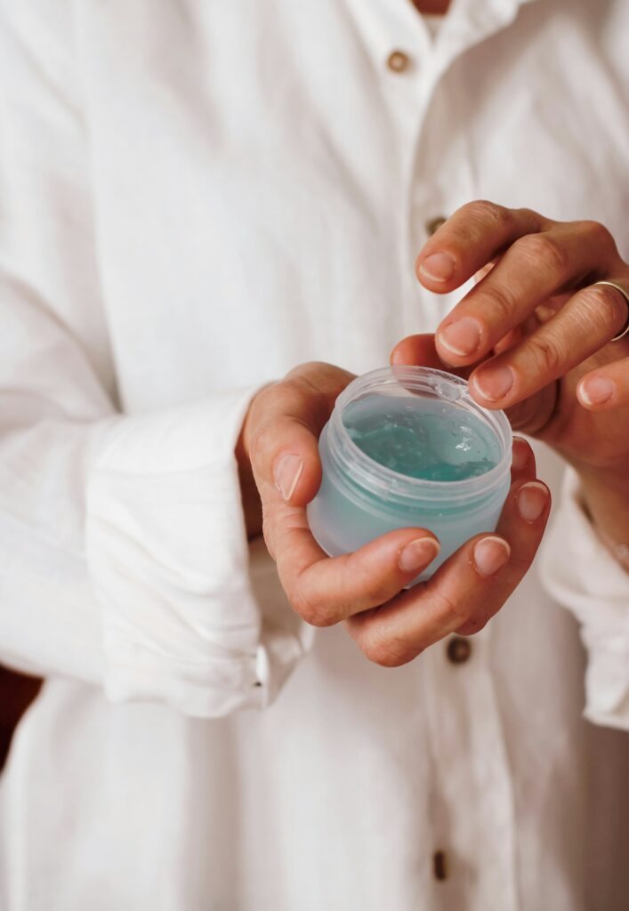 Close up of a hand dipping into a jar of blue jelly lotion