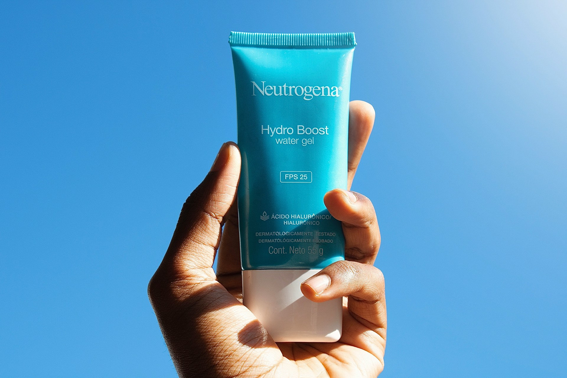 Hand holds up a blue tube of Neutrogena Hydro Boost face lotion