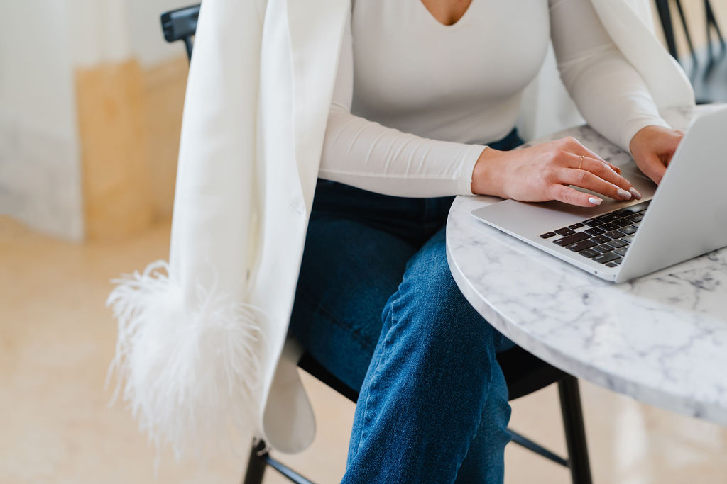 Close up detail of woman doing taxes on her laptop at a small white marble cafe table